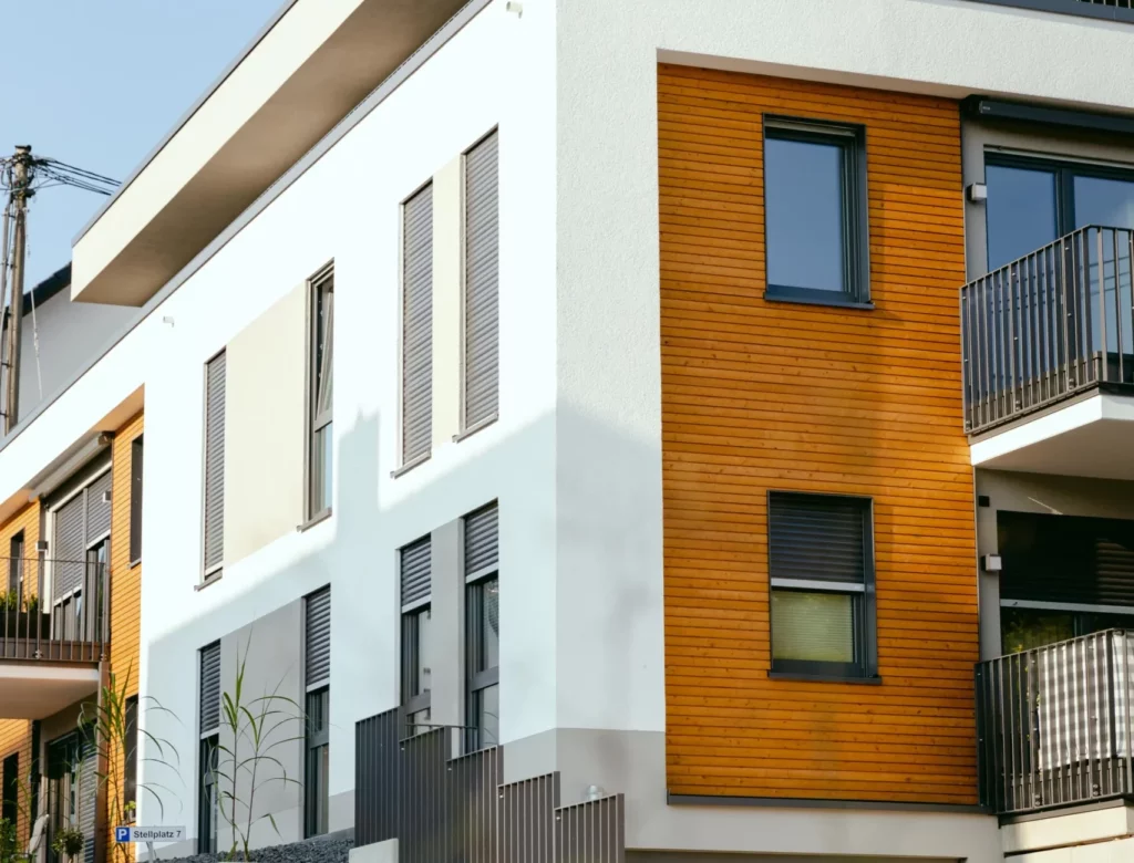 Mehrfamilienhaus mit weiße Hauswand und Holzelementen zwischen den Balkonen